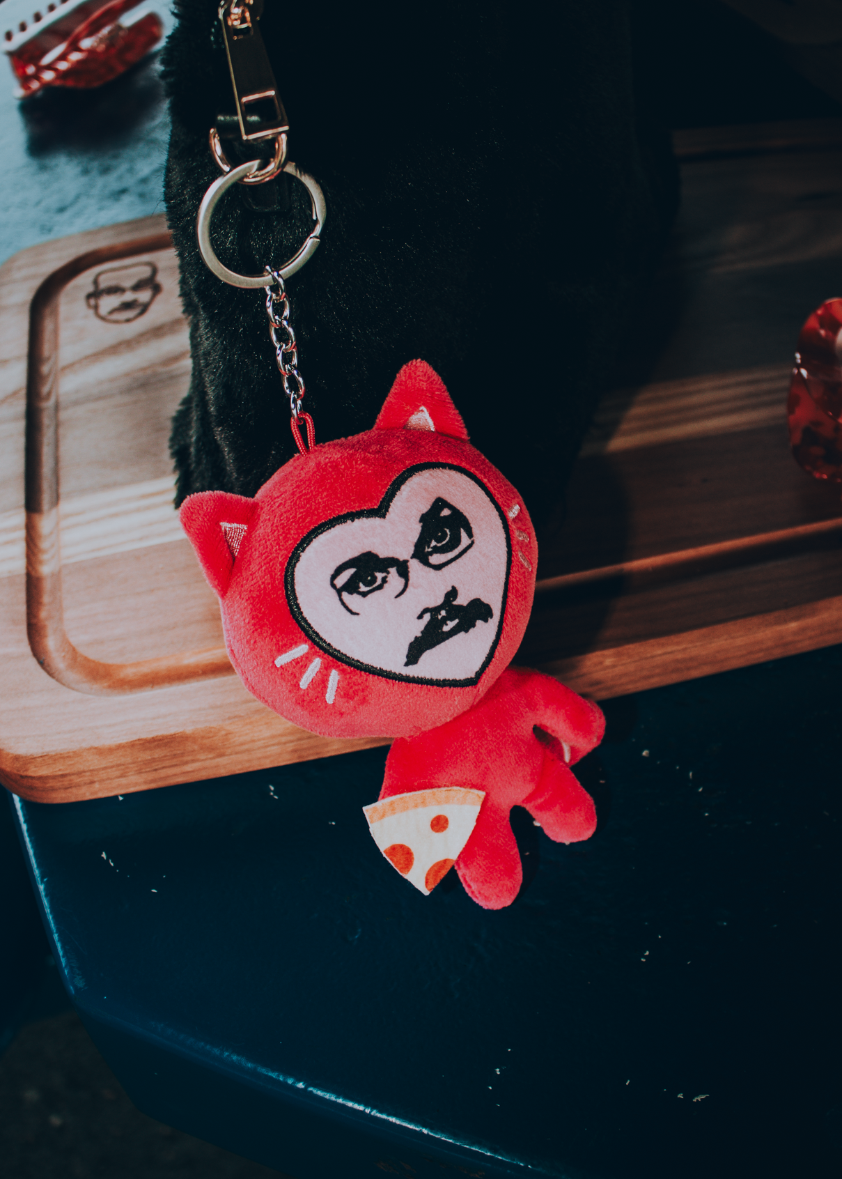 Pink plush keychain in the shape of a cartoon cat, holding a pizza, with Pizza John's face