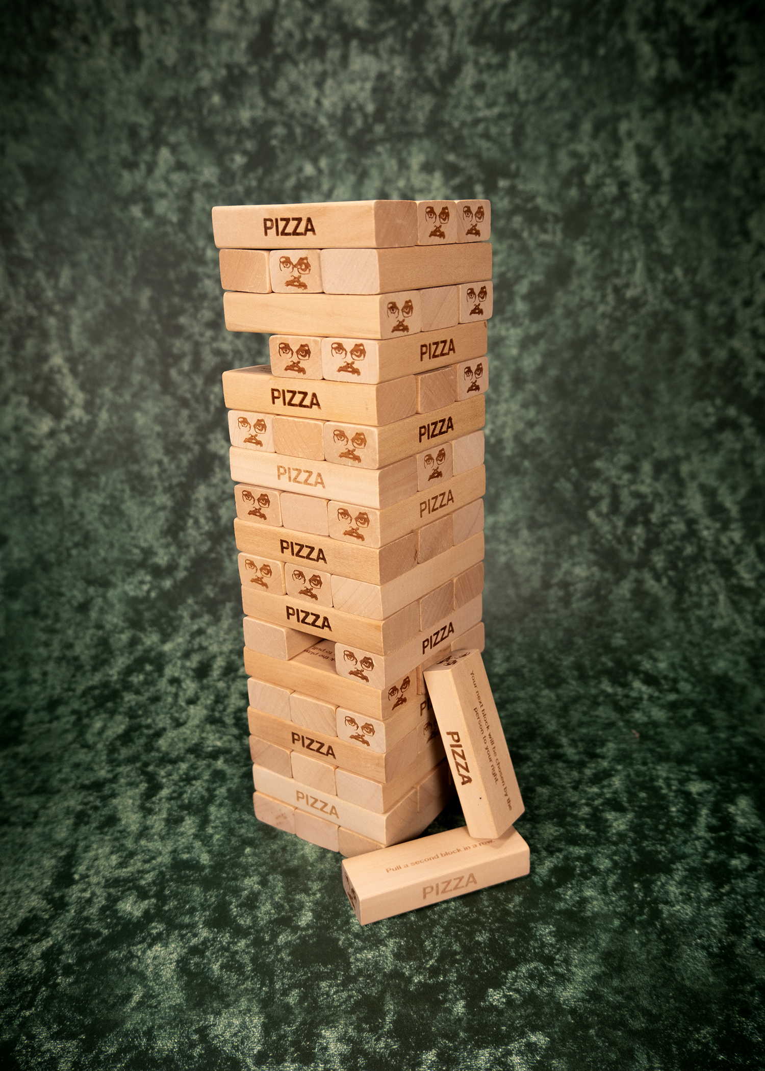 Stack of pizza-themed wooden blocks on a textured green background