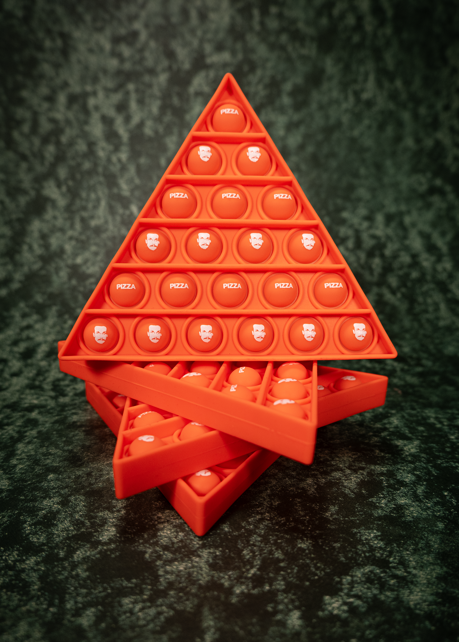 Red pyramid-shaped pop-it fidget toy on a dark textured surface